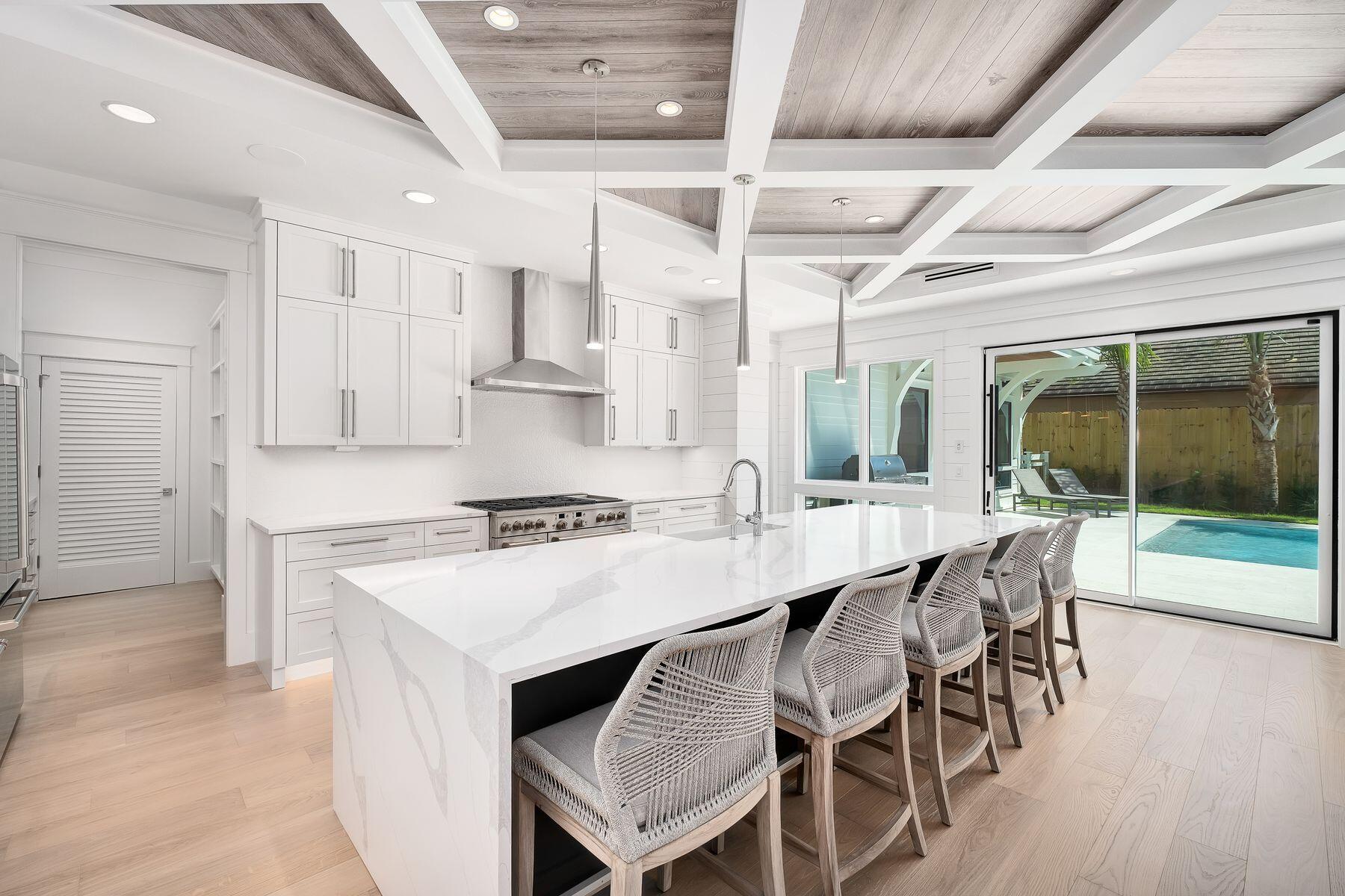 56 Pelican Glide Lane Seacrest, FL 32461 - Photo 13 of 55 a kitchen with stainless steel appliances granite countertop a stove a refrigerator and a dining table with wooden floors