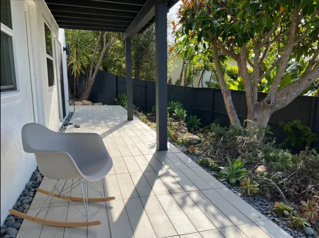 a view of a patio with table and chairs potted plants with wooden floor and fence