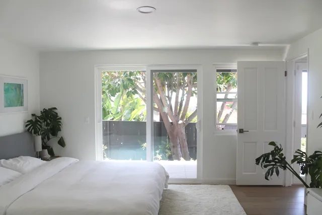 a bedroom with a large bed and a potted plant
