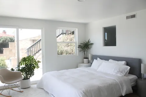 a bedroom with a large bed and a potted plant