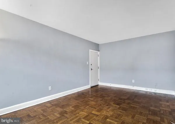 a view of an empty room with kitchen and a window