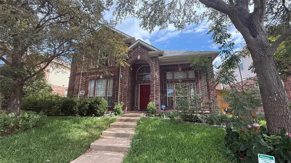 a view of a brick house with a large windows plants and large trees