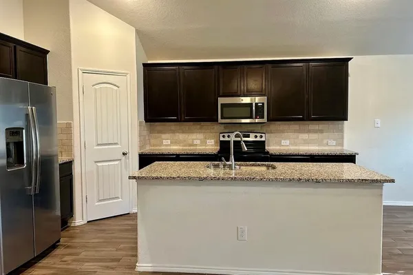 a kitchen with granite countertop a refrigerator and a sink