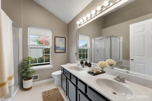a bathroom with a double vanity sink a toilet and a large mirror