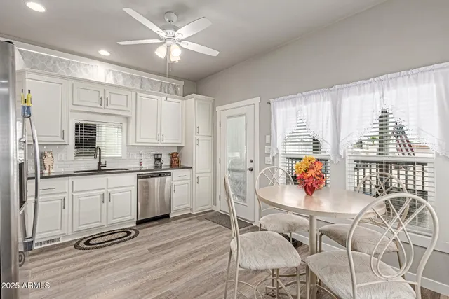 a kitchen with stainless steel appliances granite countertop a stove a sink a dining table and chairs with wooden floor