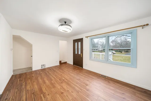 a view of an empty room with a window and wooden floor