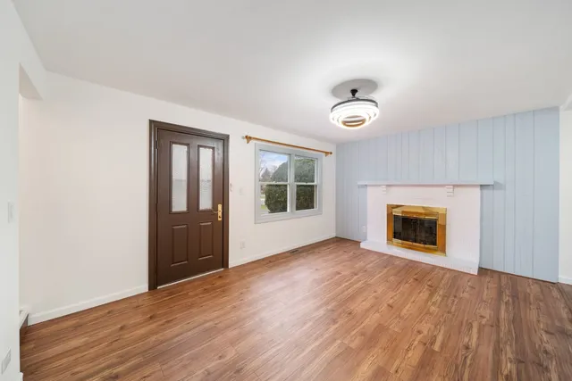 an empty room with wooden floor fireplace and windows