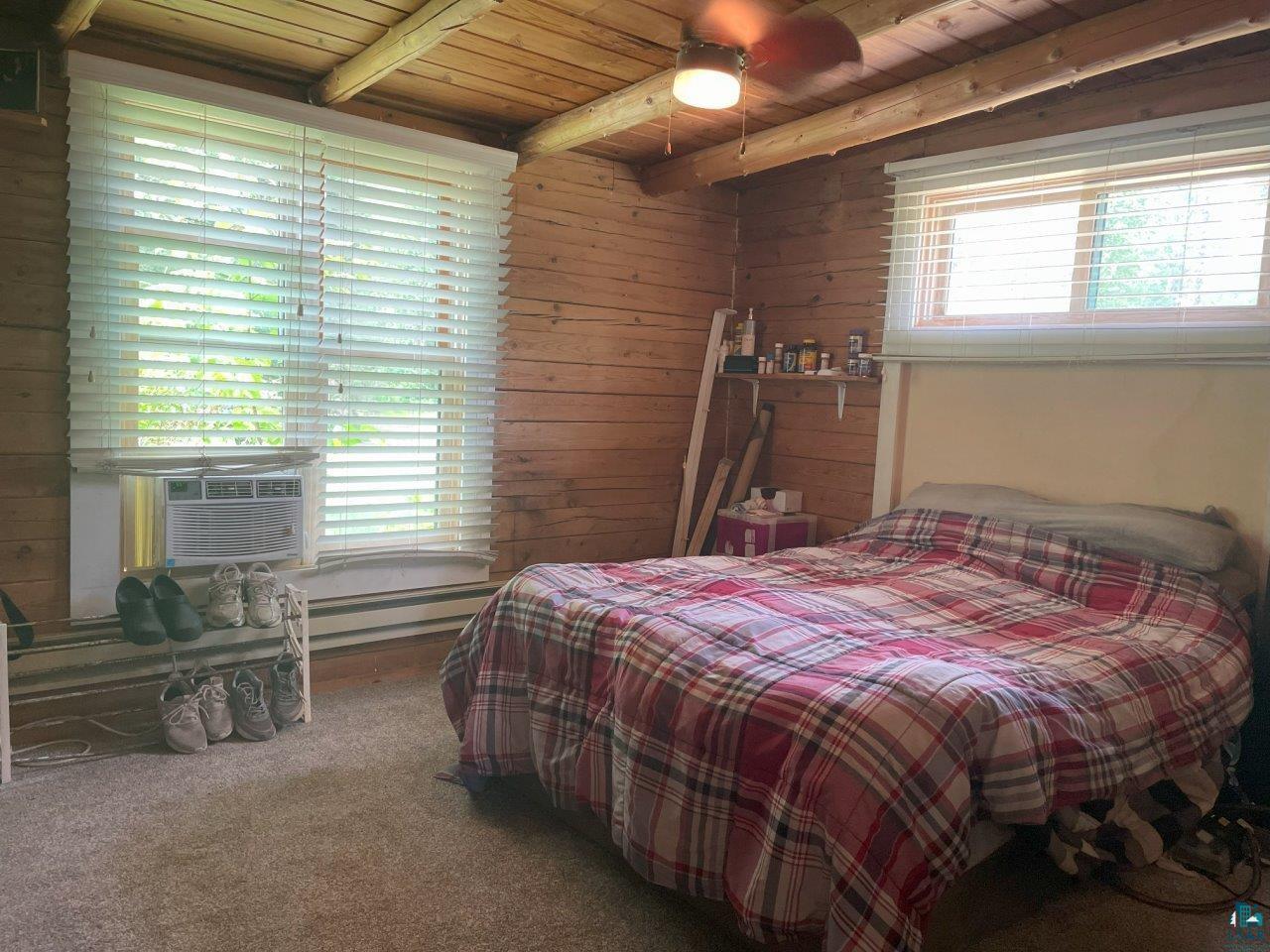 3420 Dewees Road Babbitt, MN 55706 - Photo 19 of 58 Bedroom featuring a wood ceiling with exposed beams, carpet, wood walls, a baseboard heating unit, and cooling unit
