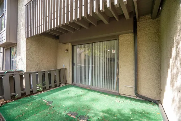 a view of the patio with dining table and chairs under an umbrella