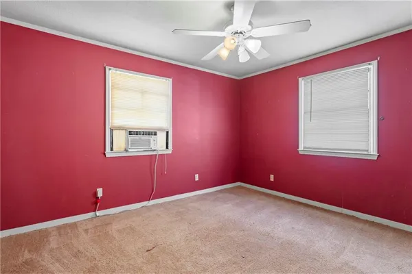 an empty room with chandelier fan and windows