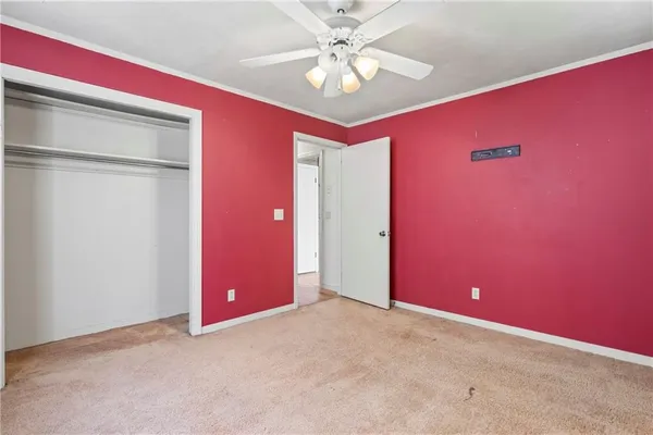 an empty room with a chandelier fan and windows