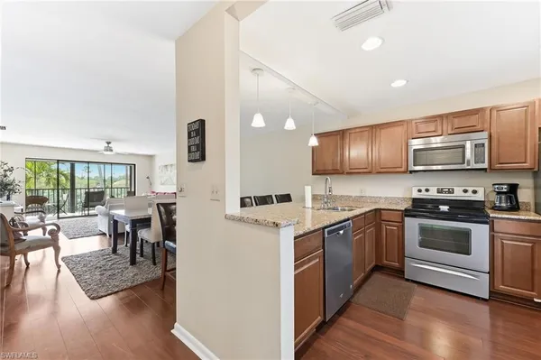 a kitchen with stainless steel appliances granite countertop a stove top oven a sink dishwasher a dining table and chairs with wooden floor
