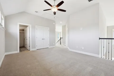 an empty room with ceiling fan and windows