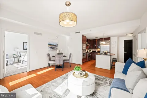 a living room with furniture kitchen view and a wooden floor