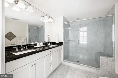 a bathroom with a double vanity sink a large mirror and shower