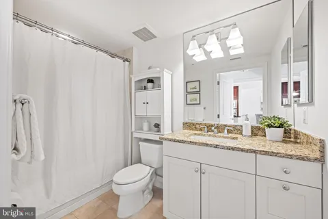 a bathroom with a granite countertop sink toilet and mirror