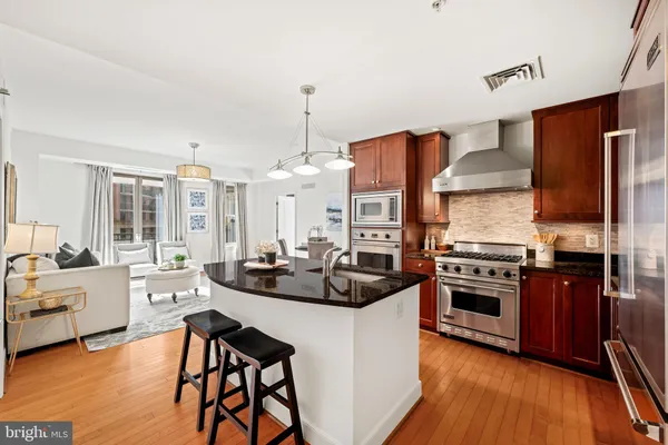 a kitchen with stainless steel appliances a stove a sink a oven a dining table and chairs