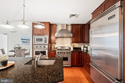 a kitchen with stainless steel appliances granite countertop a stove refrigerator and cabinets