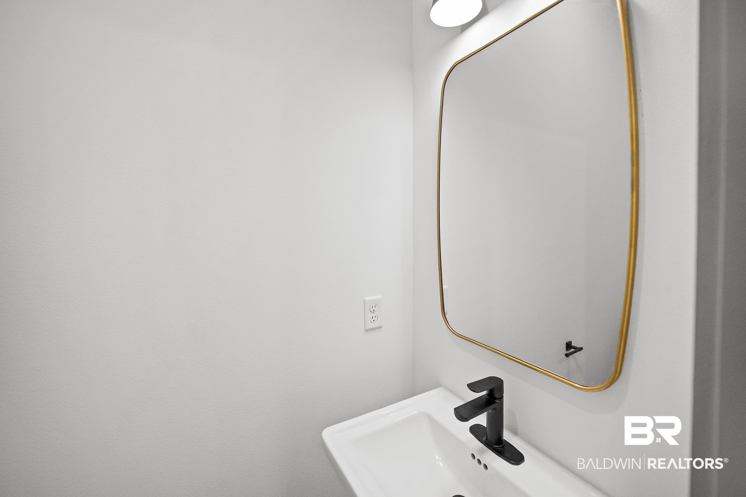 13111 Gopher Court Elberta, AL 36530 - Photo 26 of 41 White pedestal sink featuring a matte black single-handle faucet, illuminated by an overhead light fixture