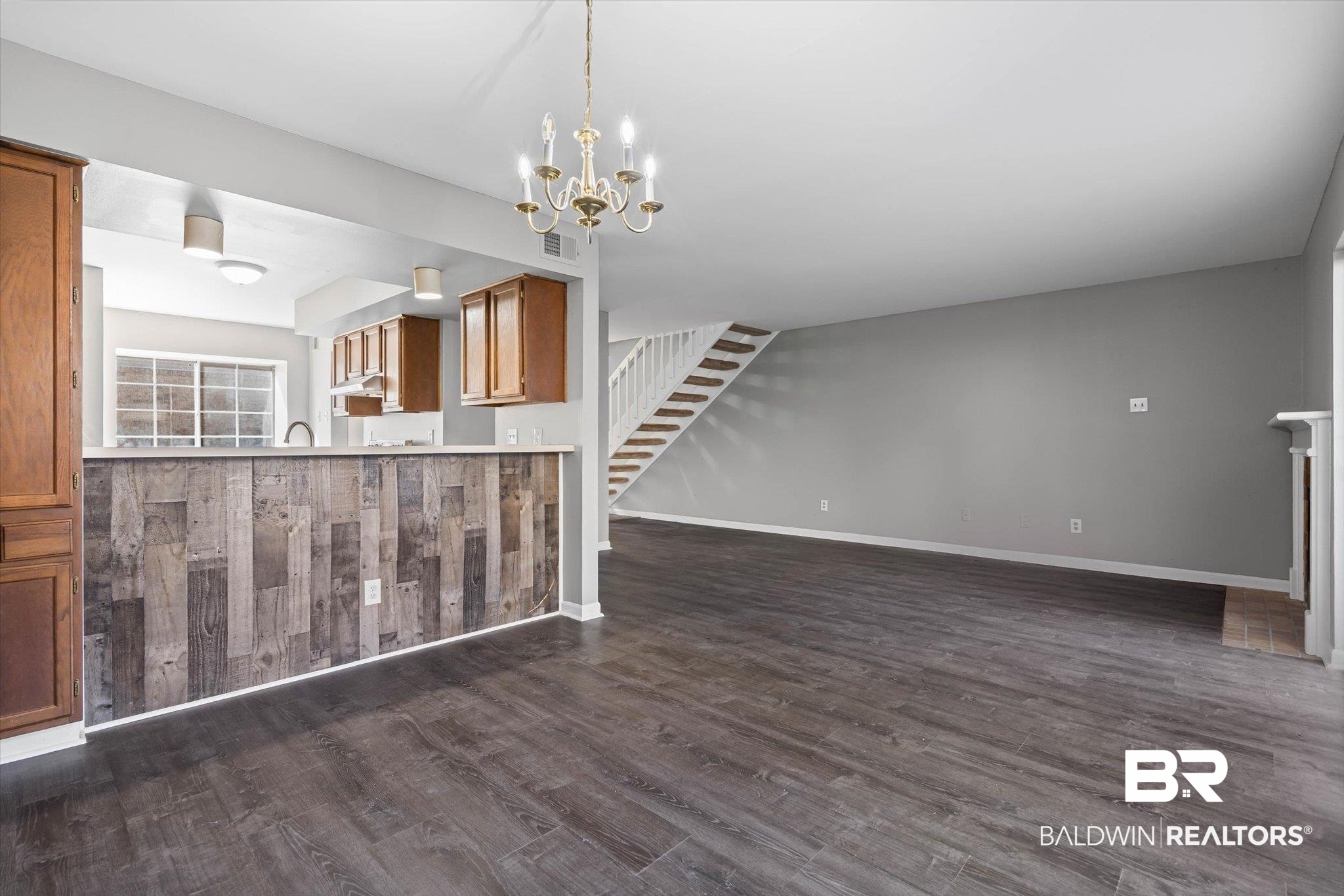 6701 Dickens Ferry Road, Unit 100 Mobile, AL 36608 - Photo 7 of 24 Unfurnished living room with dark wood finished floors, a chandelier, and stairway