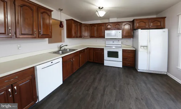 a kitchen with stainless steel appliances granite countertop wooden cabinets a sink a stove a refrigerator and island with wooden floors