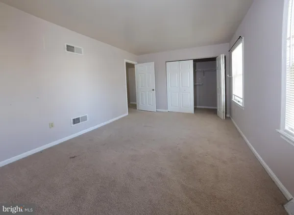 a view of an empty room with closet and a window