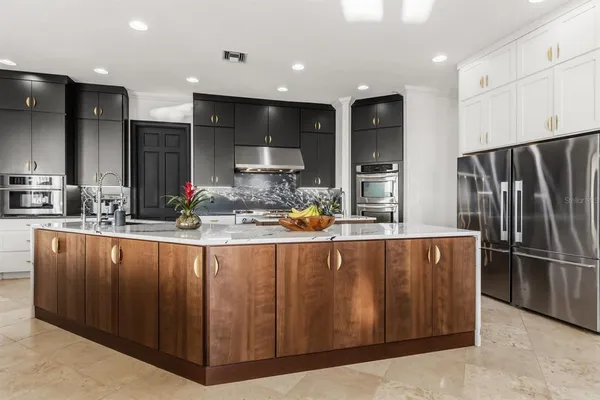 a large kitchen with stainless steel appliances lots of counter space and a sink