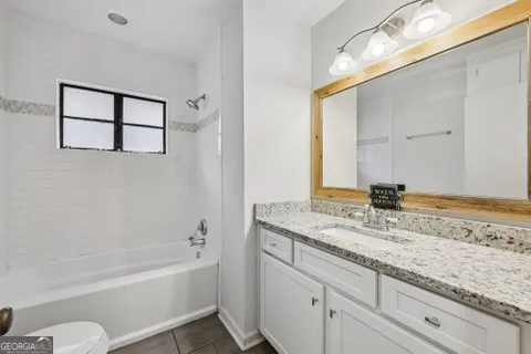 a bathroom with a granite countertop sink mirror toilet and bathtub