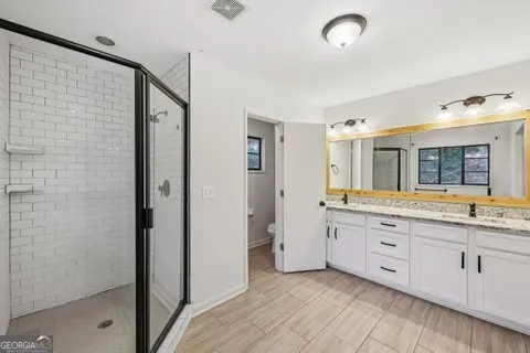 a spacious bathroom with a granite countertop sink a mirror and a shower
