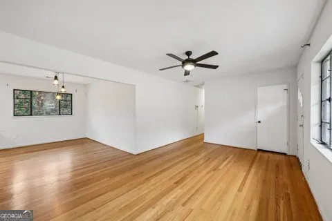 an empty room with wooden floor and windows