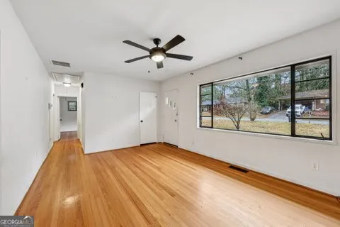 a view of empty room with wooden floor and fan
