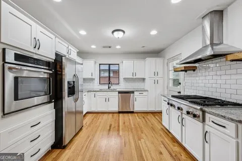 a kitchen with stainless steel appliances a refrigerator a stove and white cabinets