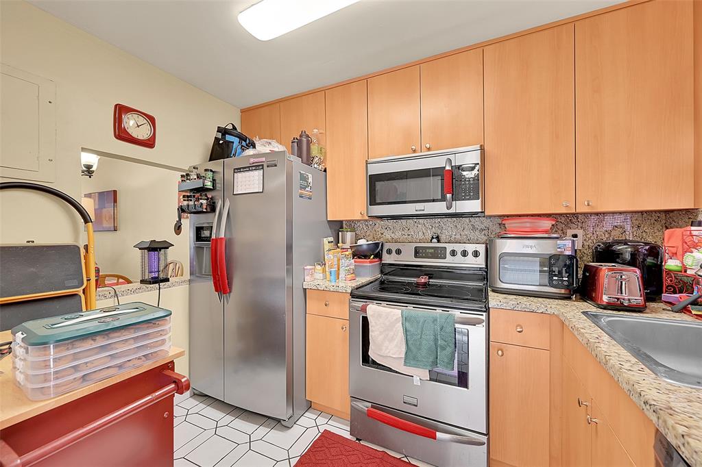 2811 North Pine Island Road, Unit 111 Sunrise, FL 33322 - Photo 10 of 13 a kitchen with stainless steel appliances granite countertop a refrigerator stove and sink
