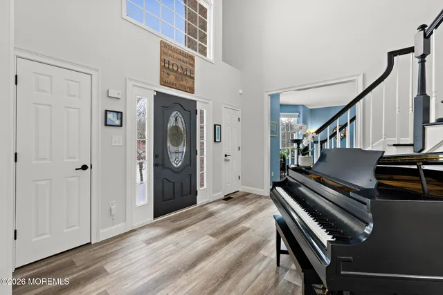 a kitchen with kitchen island granite countertop a refrigerator a stove a microwave oven a sink dishwasher and white cabinets with wooden floor