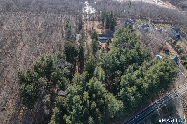 an aerial view of residential house with outdoor space and trees all around