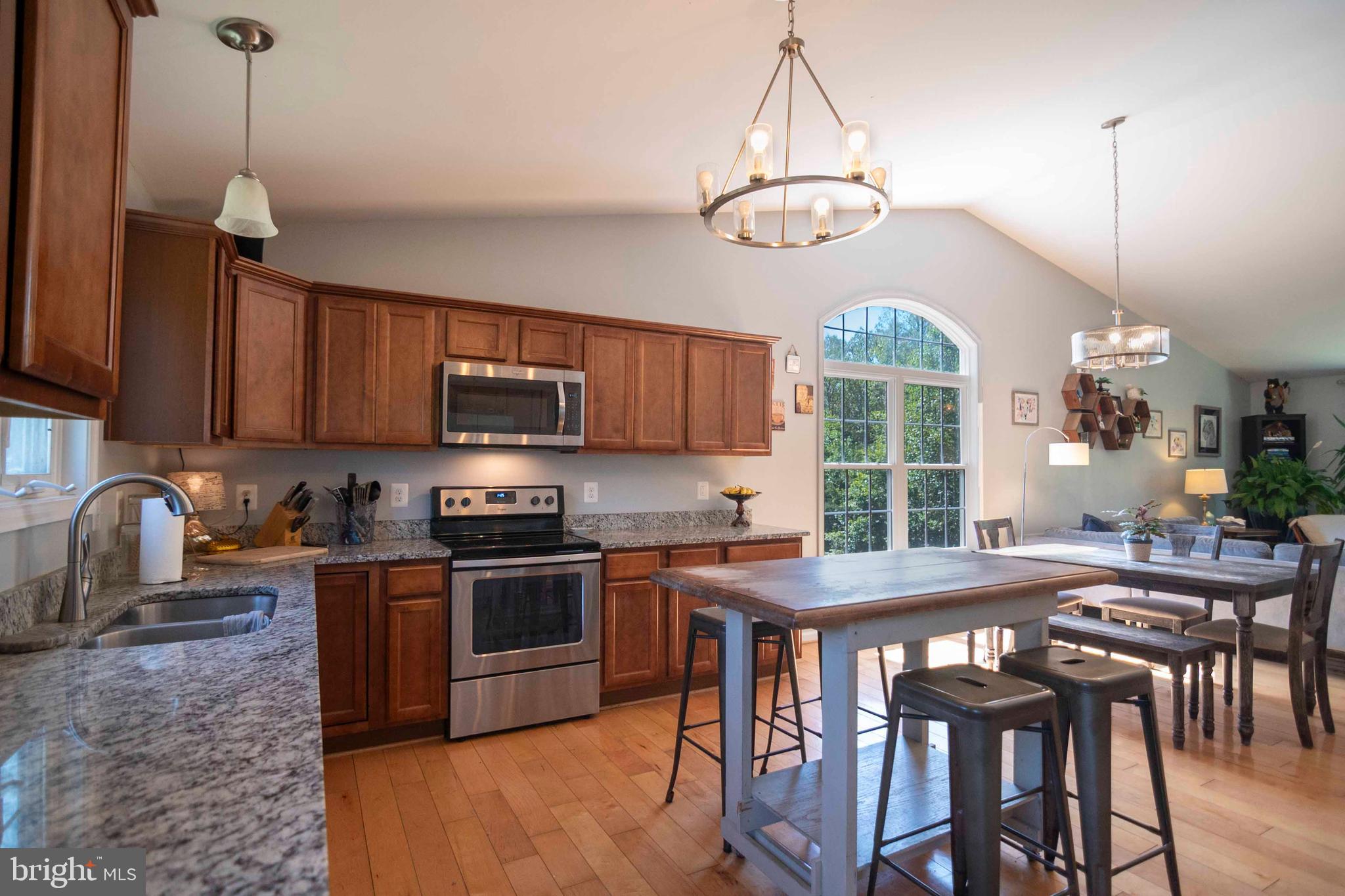 21281 Old Mill Road Culpeper, VA 22701 - Photo 27 of 40 a kitchen with stainless steel appliances granite countertop a stove a sink a refrigerator a stove a dining table and chairs with wooden floor