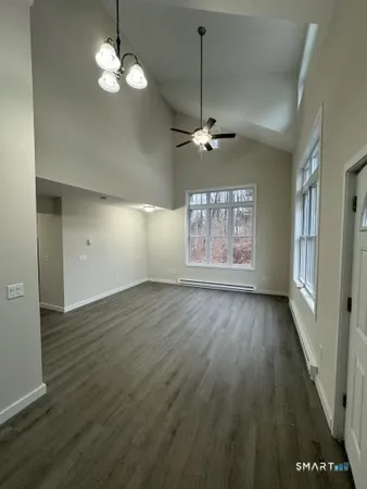 an empty room with wooden floor chandelier and windows