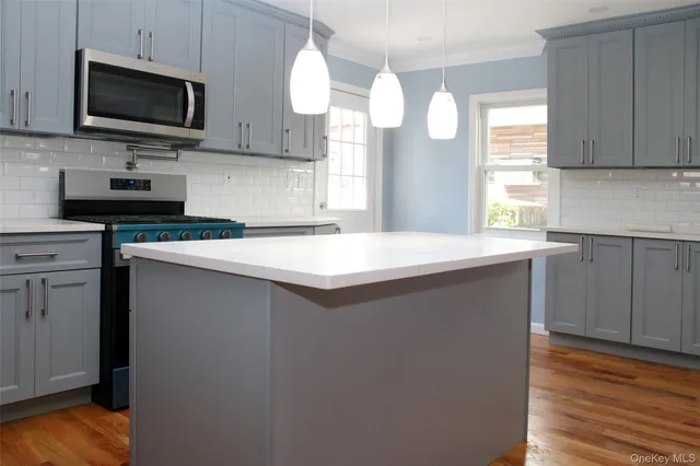 a kitchen with kitchen island granite countertop stainless steel appliances a sink cabinets and a window