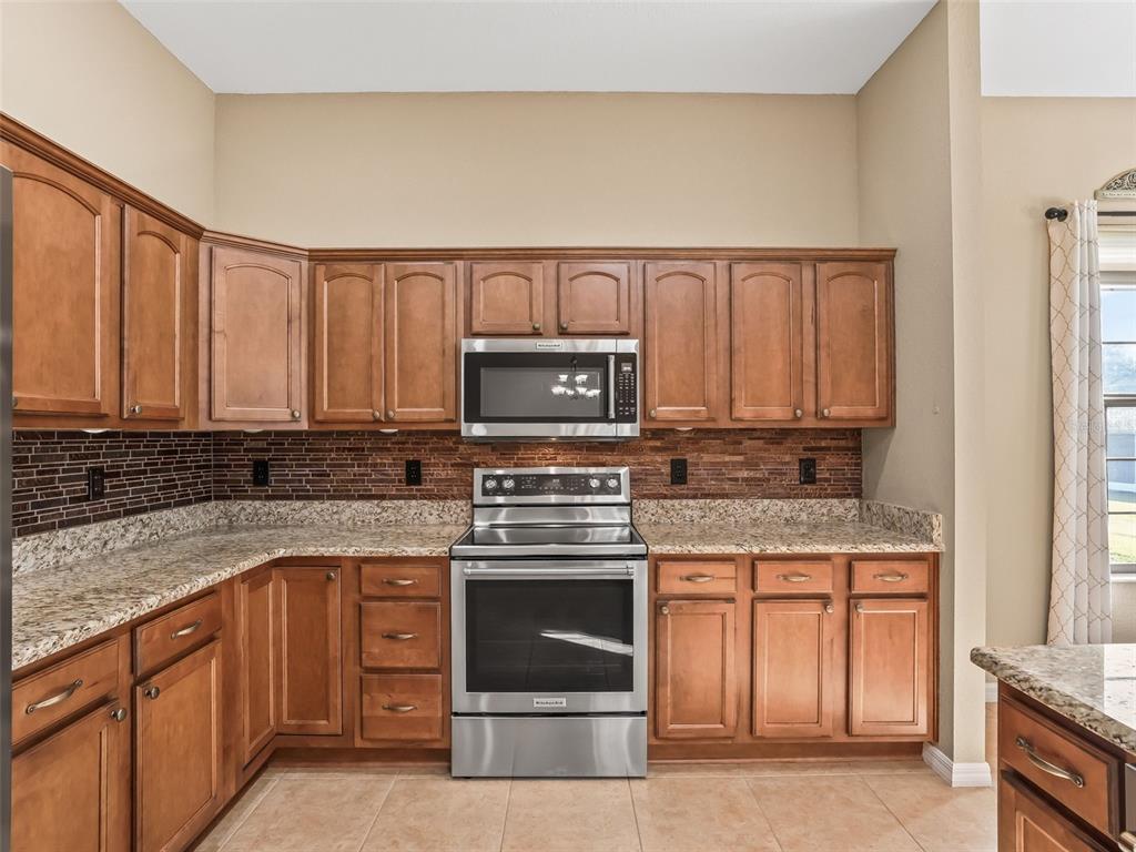 16896 South East 110th Court Road Summerfield, FL 34491 - Photo 23 of 61 a kitchen with granite countertop a stove top oven microwave and cabinets