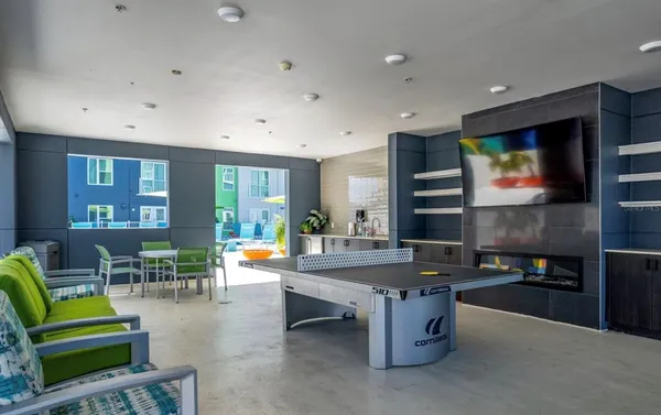 a living room with furniture pool table kitchen view and a flat screen tv