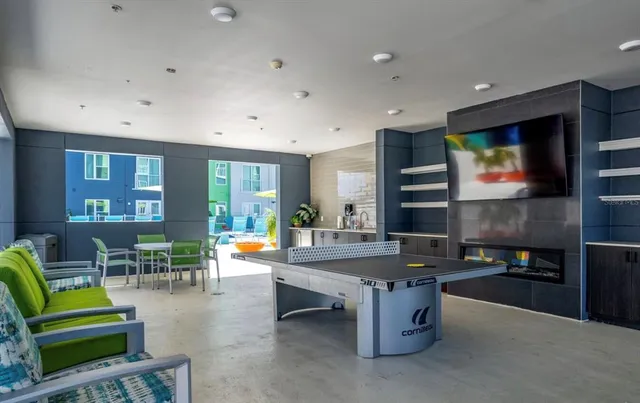 a living room with furniture pool table kitchen view and a flat screen tv