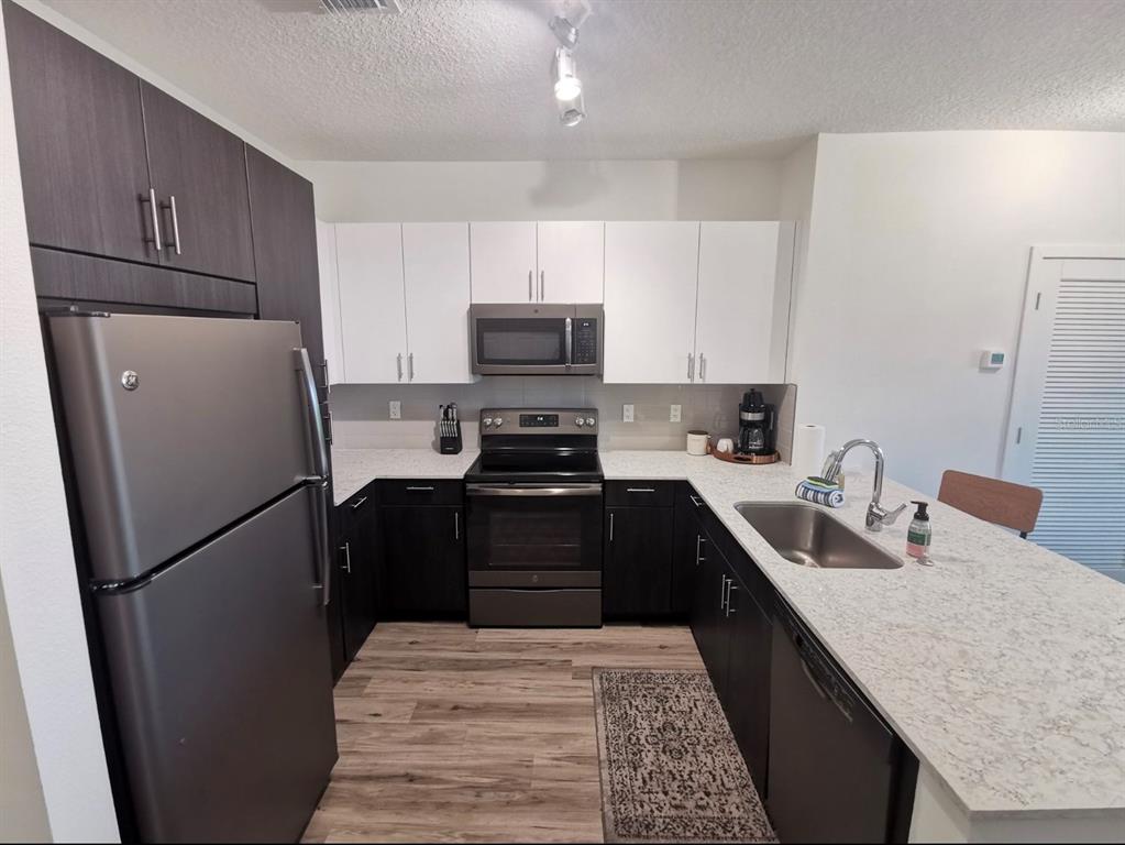 1659 2nd Street, Unit 515 Sarasota, FL 34236 - Photo 5 of 21 a kitchen with a refrigerator sink and wooden cabinets