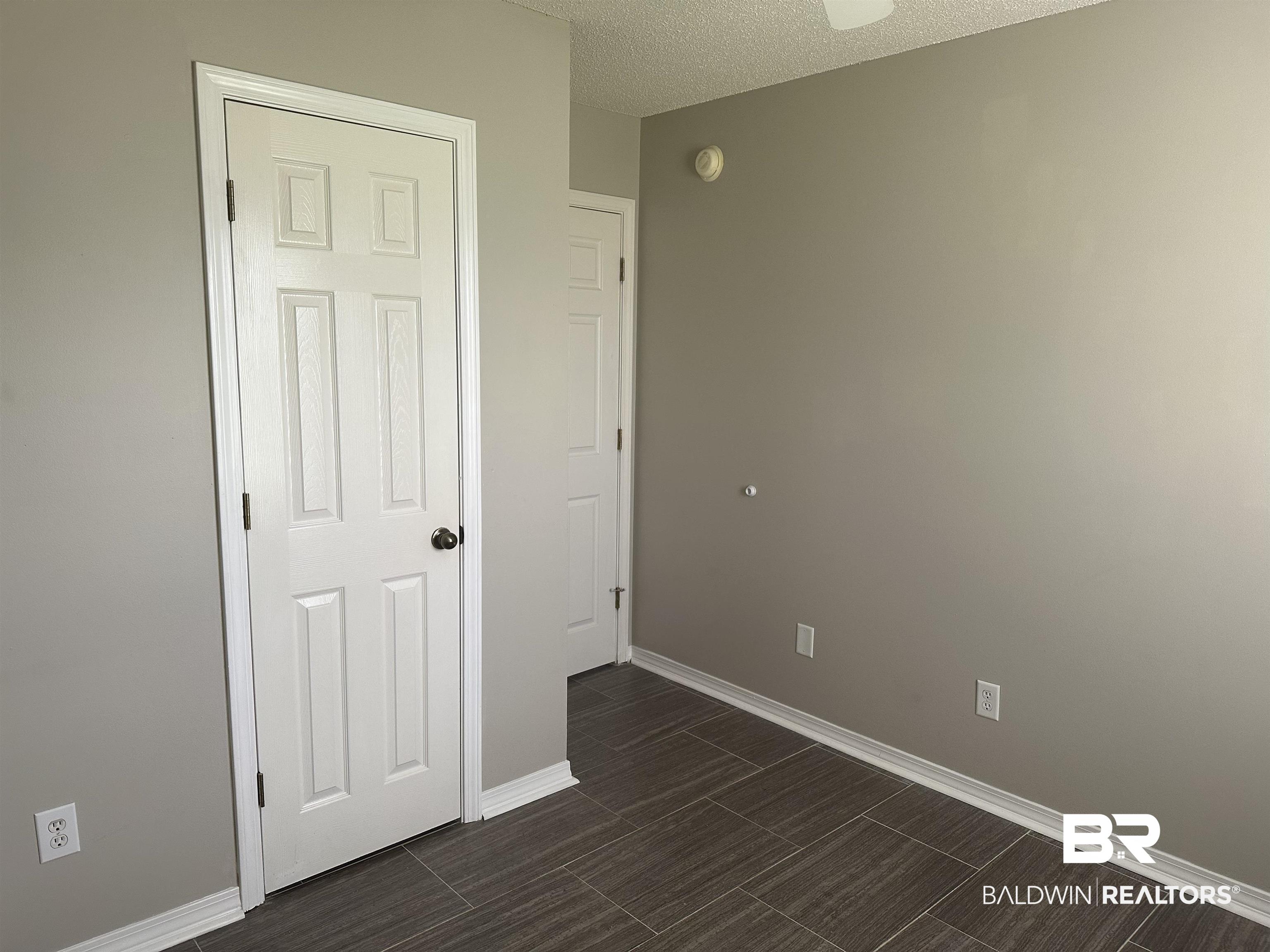 4882 Rebecca Place Mobile, AL 36695 - Photo 20 of 29 Unfurnished bedroom featuring a textured ceiling, baseboards, and wood tiled floor