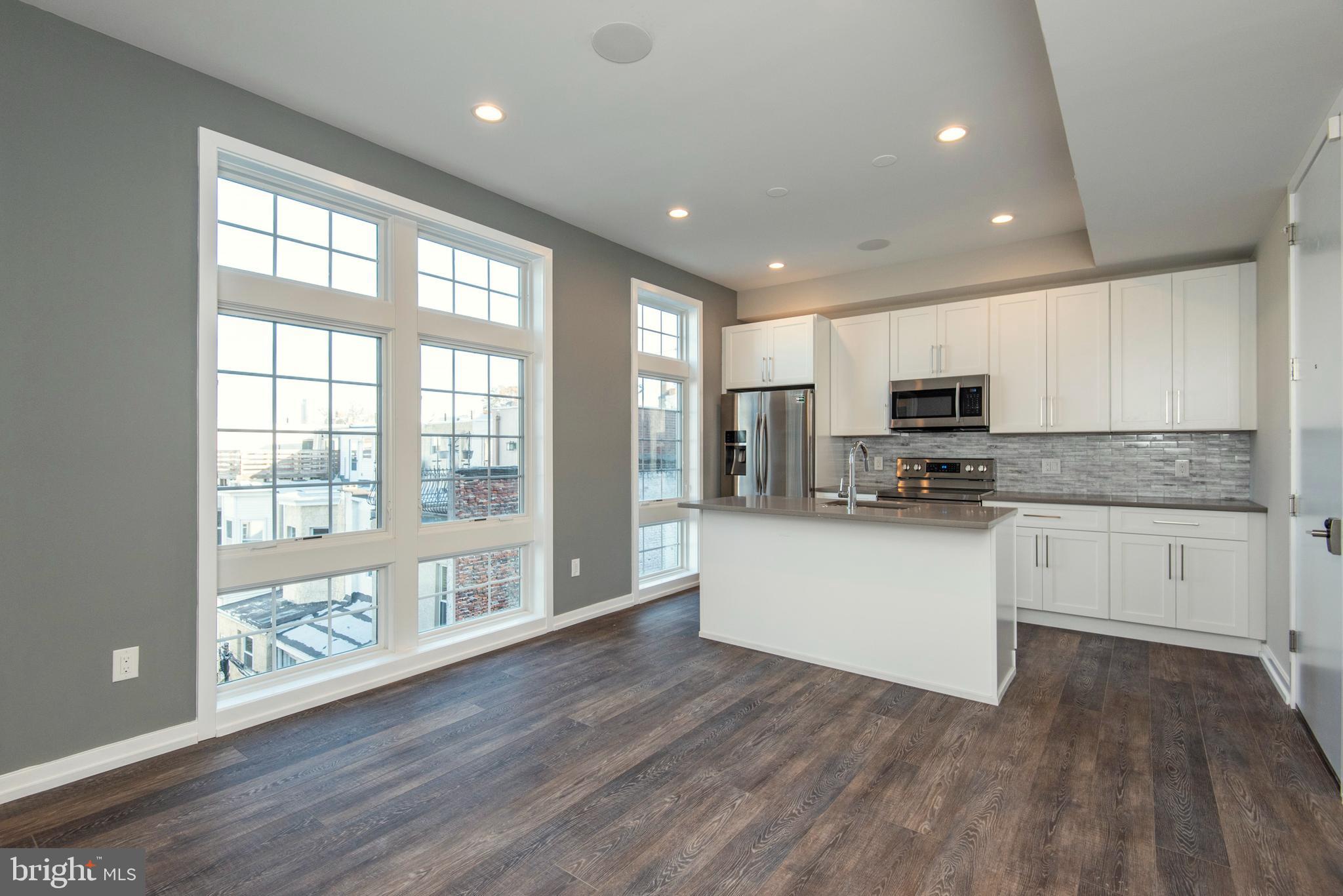 1340 South 13th Street, Unit 3B Philadelphia, PA 19147 - Photo 3 of 31 a kitchen with stainless steel appliances granite countertop a refrigerator a sink dishwasher a stove and white countertops with wooden floor