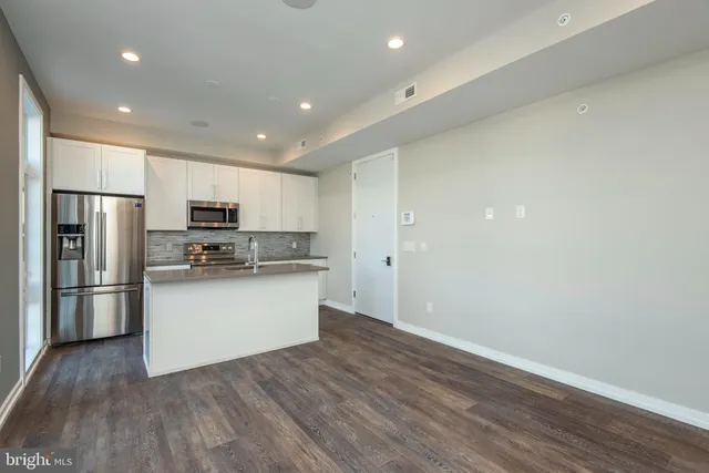a kitchen with stainless steel appliances a refrigerator and wooden floor