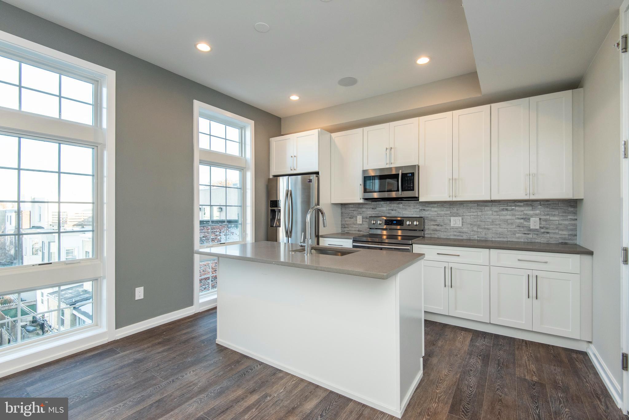 1340 South 13th Street, Unit 3B Philadelphia, PA 19147 - Photo 5 of 31 a kitchen with granite countertop white cabinets and wooden floor