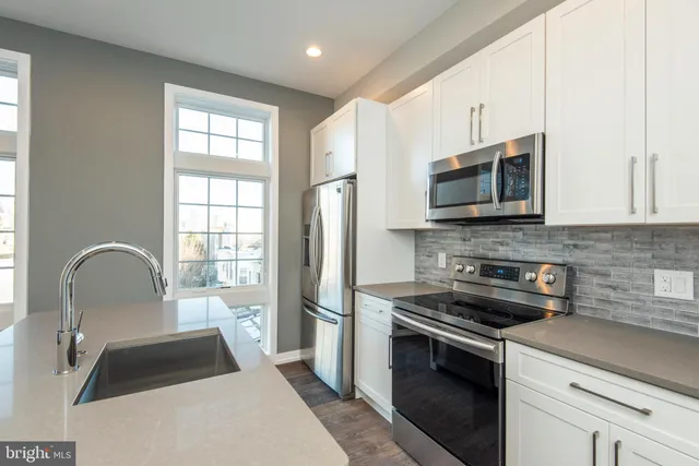 a kitchen with a microwave a stove a sink dishwasher a refrigerator with white cabinets and wooden floor