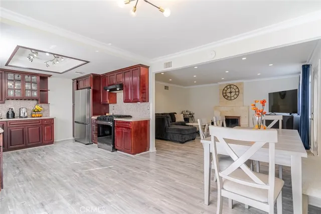 a kitchen with stainless steel appliances kitchen island granite countertop a stove top oven a sink dishwasher and a dining table with wooden floor