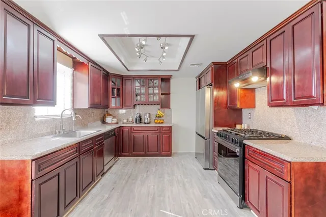 a kitchen with stainless steel appliances granite countertop a stove a sink dishwasher and cabinets with wooden floor