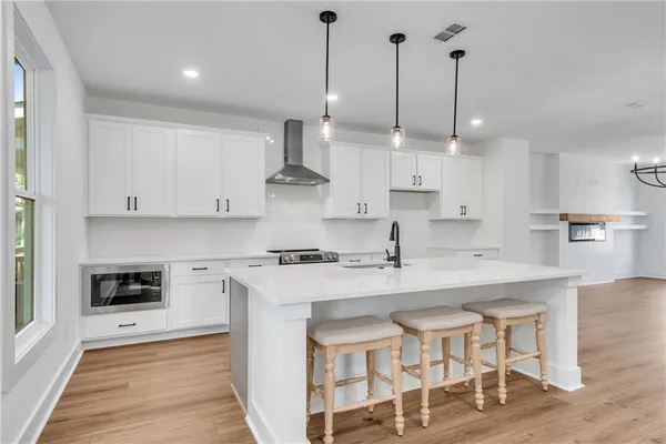 a kitchen with stainless steel appliances kitchen island a table chairs sink and cabinets